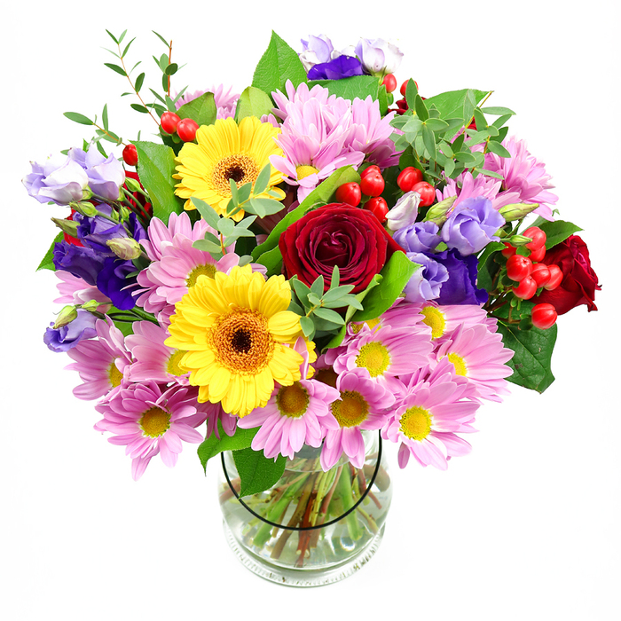 A generous, hand-crafted bouquet stands tall in a transparent glass vase, set before a plain white background that emphasises the richness of the colours. At its centre, classic red roses spiral open, their velvety petals layered deeply to create a romantic focal point that would be just as at home in an Amersham townhouse as in a cosy cottage near the Chiltern hills. Flanking the roses are two glowing yellow gerbera daisies with dark brown-orange centres, their round, flat flower heads like small suns radiating warmth and joy. Encircling these key blooms, an abundance of pink and lilac-toned chrysanthemums and daisy-style flowers form a soft collar, each bloom a cluster of fine petals surrounding tiny yellow hearts. These daisies lend the bouquet a comforting, garden-fresh volume, as though the flowers had been gathered from a local Amersham garden in full bloom. Threaded through the pastel clouds are lisianthus blossoms in shades of purple and lavender, some opening into gentle bell-shaped flowers, others still curled as buds, adding movement and a slightly whimsical touch. Scattered among the petals, bright red hypericum berries cluster like small, polished beads, giving the arrangement a modern texture and a touch of cheerful playfulness. The whole design is framed and supported by mixed greenery: strong, deep green leaves and lighter, airy sprigs that lift the composition and accentuate the colours. The clear vase reveals the criss-crossing stems, carefully trimmed and arranged in clear water, a subtle reminder of the florist's attentive craftsmanship. The bouquet carries a feeling of celebration and kindness, ideal for birthdays, anniversaries, or simply sending a colourful message of thinking of you with same-day delivery across Amersham and the surrounding Chiltern villages.